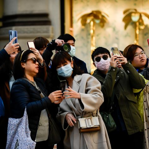 Touristen tragen Mundschutz und fotografieren mit ihren Smartphones