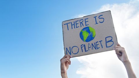Klimafasten im Selbstversuch: Ein Mann hält ein Protestschild hoch