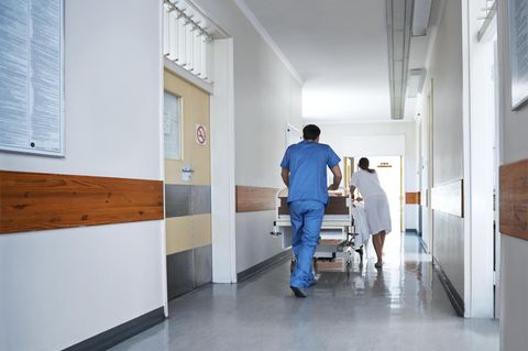 Ärzte schieben einen Verletzen in einem Bett durch einen Krankenhausflur