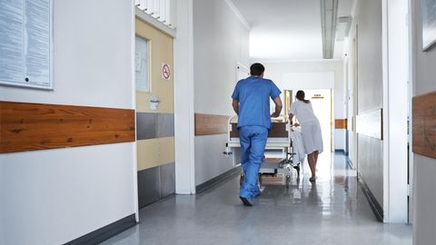 Ärzte schieben einen Verletzen in einem Bett durch einen Krankenhausflur