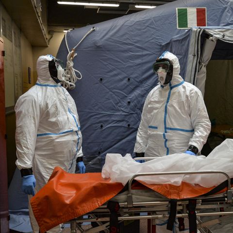 Turin: Zwei Mitarbeiter in Schutzanzügen stehen in einem Krankenhaus neben einer Liege