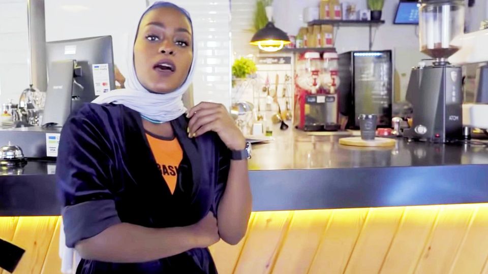 Asayel Rap Mekka Saudi-Arabien Vor dem Tresen eines Cafés steht eine junge Frau mit Kopftuch und rappt
