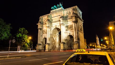 Ein Taxi steht nachts vor dem Siegestor in München