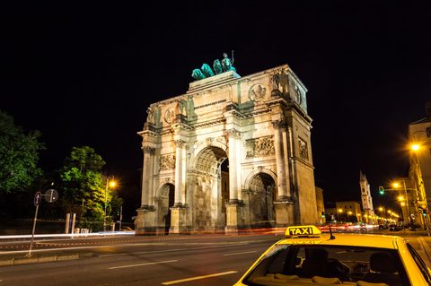 Ein Taxi steht nachts vor dem Siegestor in München