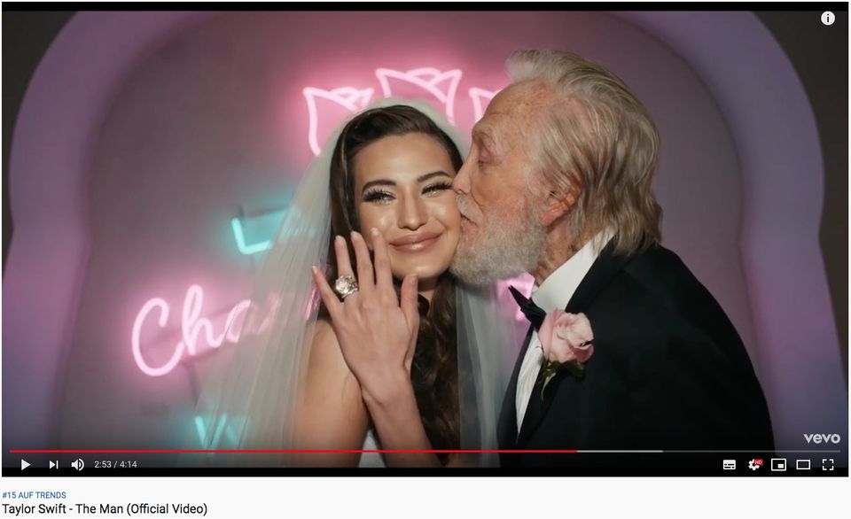 Ausschnitt aus dem Musikvideo zu "The Man" Ausschnitt aus dem Musikvideo zu "The Man": Eine Braut hält ihre beringte Hand in die Kamera