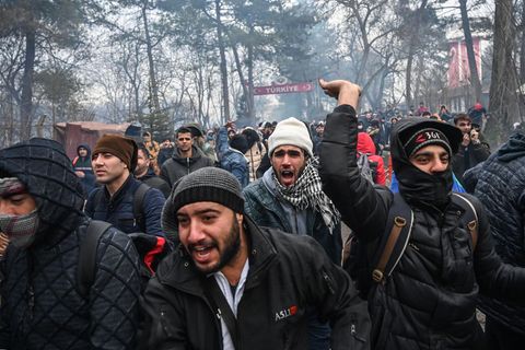 Migranten rufen und gestikulieren im türkisch-griechischen Grenzgebiet