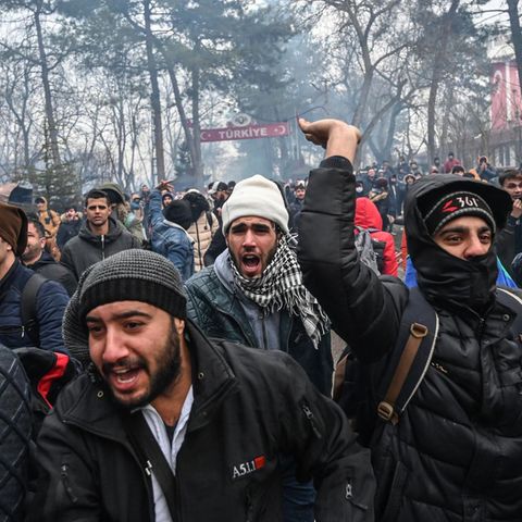 Migranten rufen und gestikulieren im türkisch-griechischen Grenzgebiet