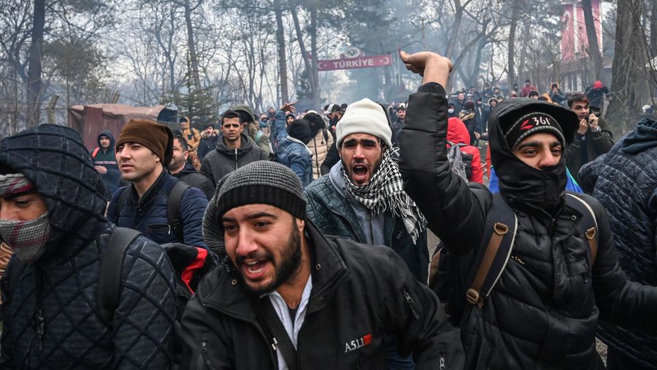 Migranten rufen und gestikulieren im türkisch-griechischen Grenzgebiet