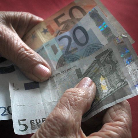 Die Hände einer alten Frau halten einen 50-, einen 20- und einen 5-Euro-Schein