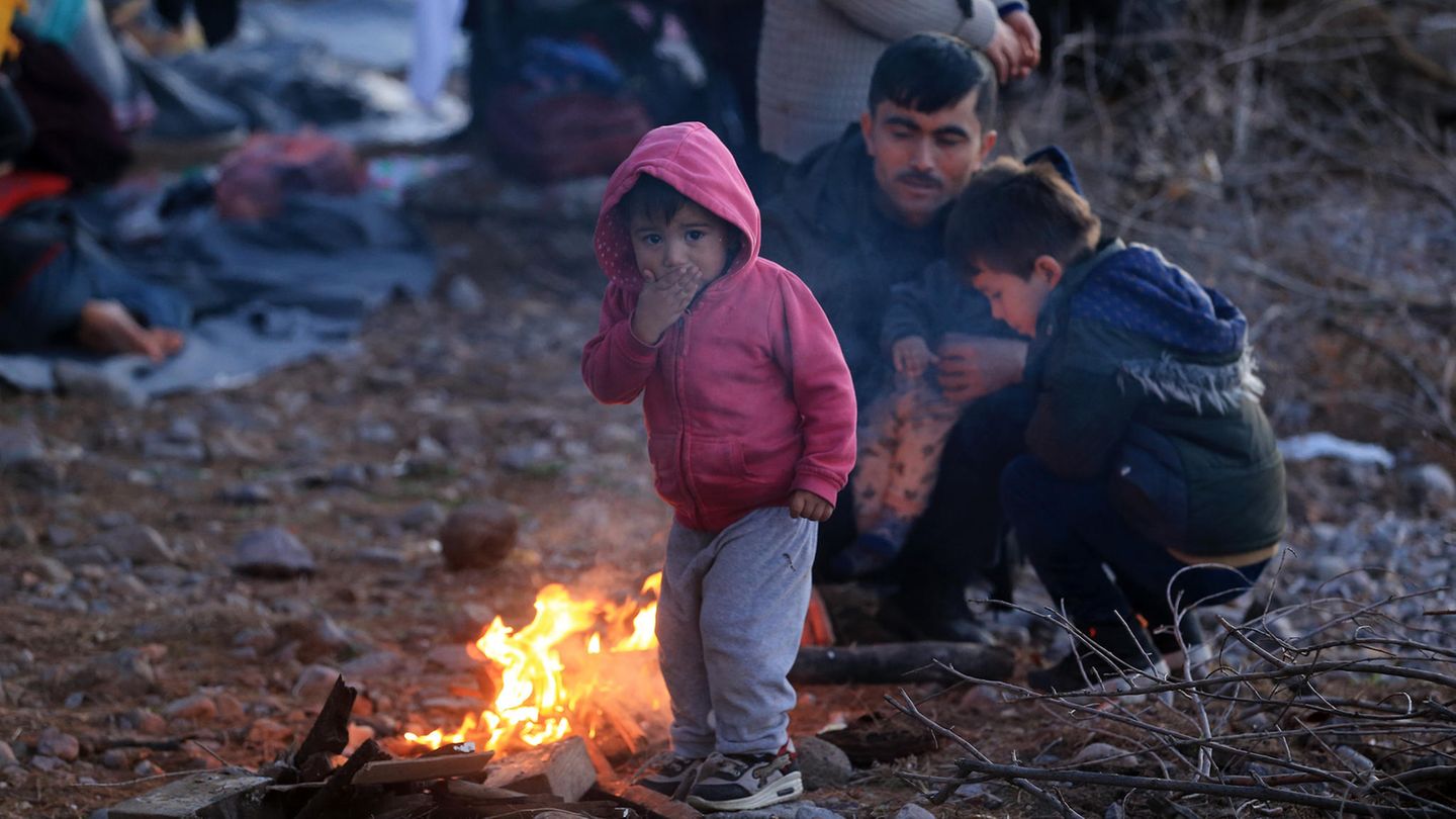 Migranten, die aus der Türkei eingetroffen sind, wärmen sich auf der Insel Lesbos an einem Feuer