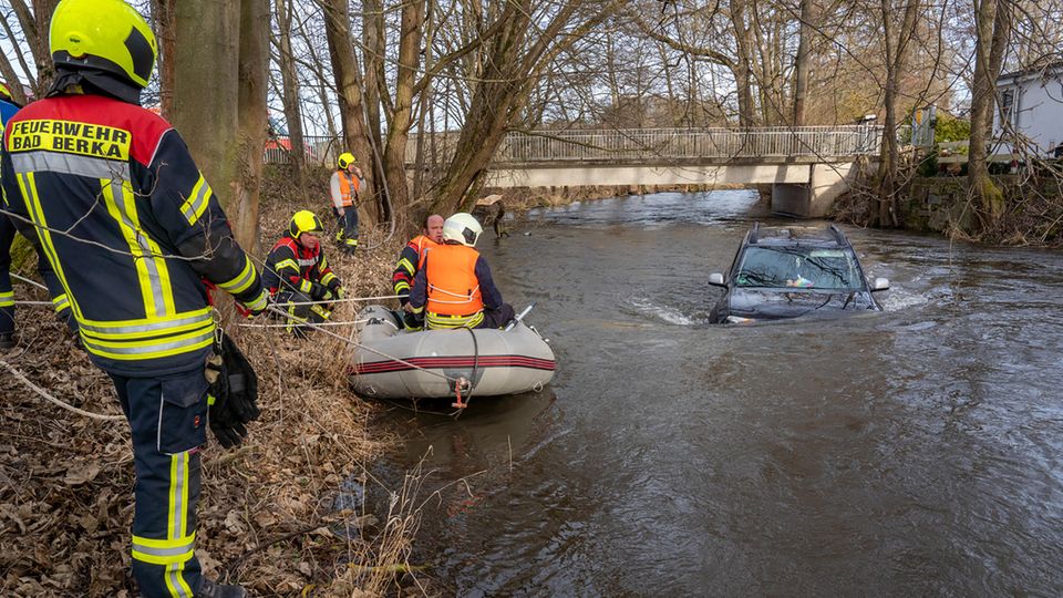 Die Feuerwehrleute versuchen ein Auto aus der Ilm zu bergen.