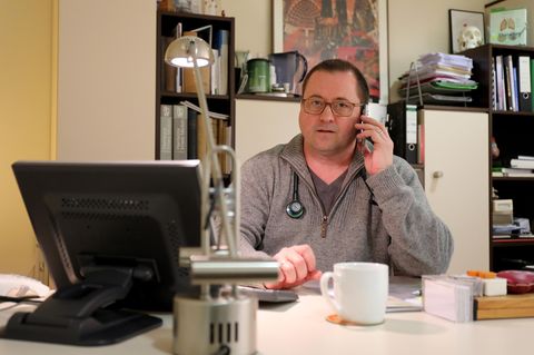 Hausarzt Coronavirus: Ein Arzt sitzt am Schreibtisch und telefoniert
