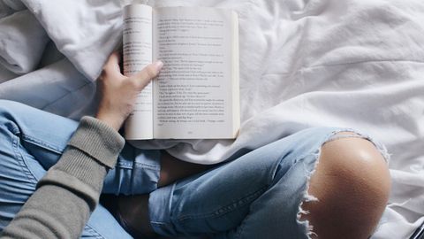 Eine Frau sitzt im Bett und liest ein Buch