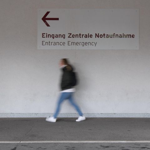 Unter einem Wegweiser "Eingang Zentrale Notaufnahme" geht eine junge Frau in Richtung des Pfeils
