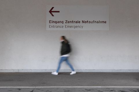 Unter einem Wegweiser "Eingang Zentrale Notaufnahme" geht eine junge Frau in Richtung des Pfeils