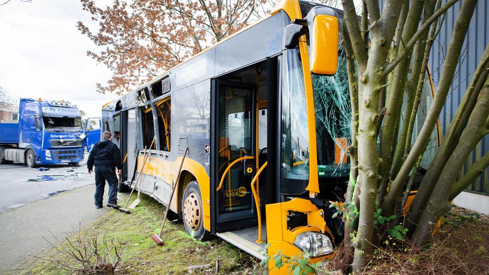 Ein beschädigter Bus steht nach einem Unfall in Troisdorf bei Köln vor einem Lastwagen