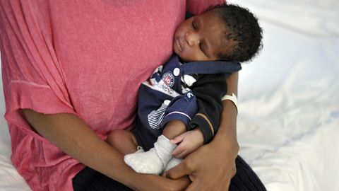 Eine schwarze Frau hält ihr Baby in den Armen