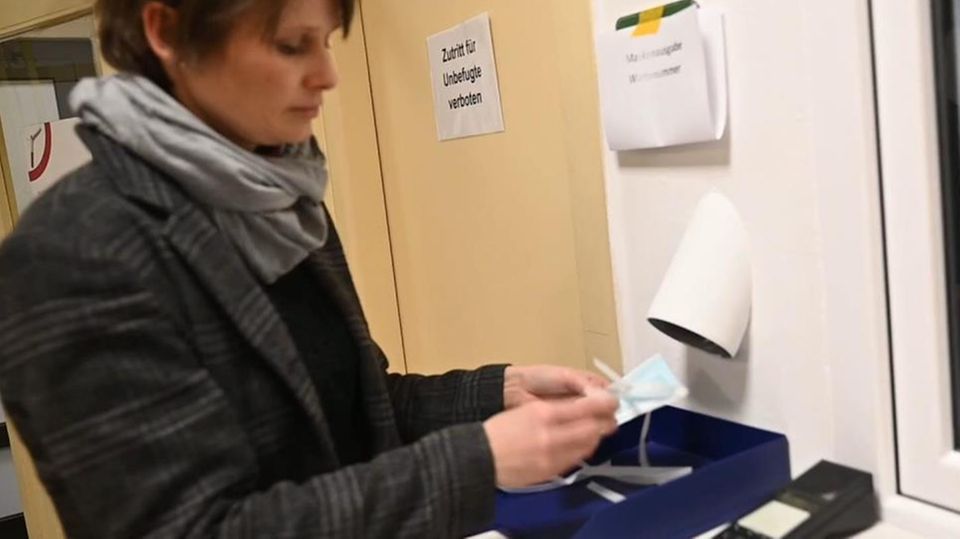 Coronavirus Abklärungsstelle Berlin Eine Frau mit kurzen, braunen Haaren steht vor einem Fenster und füllt ein Formular aus