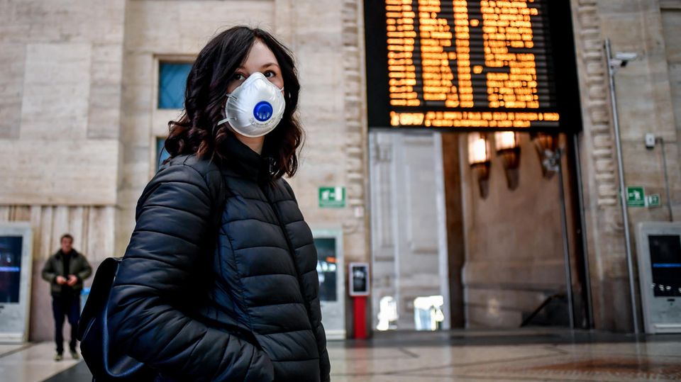 Eine Passantin mit Atemschutz steht im Hauptbahnhof von Mailand