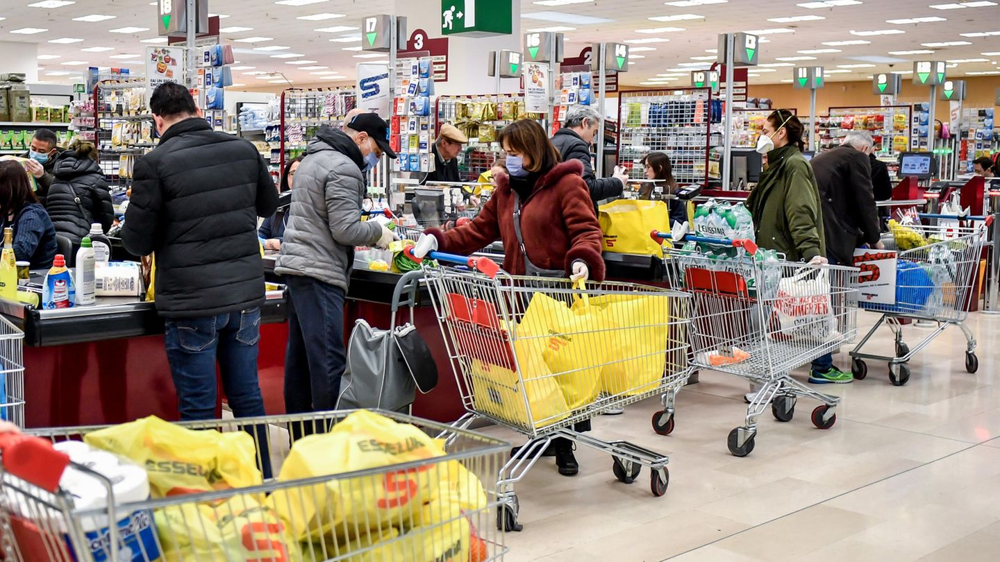 Kunden stehen im Kassenbereich eines Supermarktes