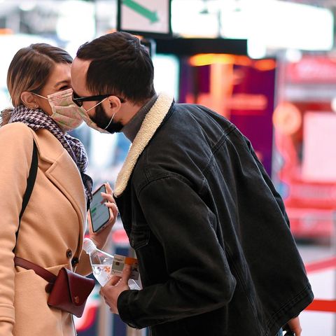 Ein Paar deutet Mundschutz tragend einen Kuss an