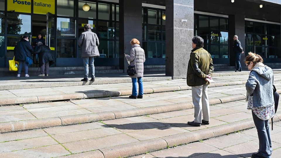 Menschen stehen vor einer Post-Filiale in Rom Schlange