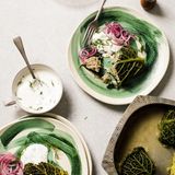 Kohlrouladen mit einer Füllung aus Schweinefleisch und Preiselbeeren      Zutaten:  1 Wirsingkohl (etwa 1 kg), Salz, 1 EL Speisestärke, 500 ml Hühnerbrühe      Füllung:  200 g Rundkornreis, 400 g Schweinehackfleisch, 1 großes Ei, 1 Lauchstange (etwa 120 g), nur weißer Teil, fein gehackt, 1 Stange Staudensellerie (etwa 60 g), geraspelt, 1 TL Fenchelsamen, zerdrückt, 2 EL getrocknete Preiselbeeren, grob gehackt, Salz, gemahlener weißer Pfeffer      Zum Servieren:  schnell eingelegte rote Zwiebel (vermischen Sie dafür die Zwiebelscheiben mit 1 TL Zucker, und lassen Sie sie 20 Min. ziehen), saure Sahne 2 EL gehackter Dill      Zubereitung:  Für die Füllung den Reis halb lange wie auf der Packung angegeben kochen. In ein Sieb abgießen den Reis abkühlen lassen. Dann mit den übrigen Zutaten, 1½ TL Salz und ½ TL Pfeffer in einer großen Schüssel gut vermengen. Beiseitestellen.  Den Backofen auf 180°C vorheizen. Mit einem scharfen Messer aus dem Boden des Kohls ein Dreieck herausschneiden, um einen Teil des Strunks und des harten Mittelteils zu entfernen. In einem großen Topf Salzwasser zum Kochen bringen. Die Hitze etwas reduzieren, den ganzen Kohl in das Wasser legen und in etwa 8 Minuten weich garen. Das Wasser abgießen und den Kohl aus dem Topf nehmen. Wenn er abgekühlt ist, 12 schöne Blätter abtrennen. Zu dicke Kohlrippen mit einem kleinen Messer herausschneiden.  Etwa 50g der Füllung mit einem Esslöffel in die Mitte eines Blattes setzen. Vom unteren Teil des Blattes aus dieses etwas einrollen, dann die linke und rechte Seite einschlagen und weiter bis nach rollen. Die Kohlpäckchen umdrehen und mit der offenen Seite nach unten in eine etwa 40 x 30 cm große Auflaufform legen. Mit den übrigen Kohlblättern und der Füllung ebenso verfahren. In einer Schüssel die Speisestärke mit 50 ml kaltem Wasser verrühren, bis die Stärke aufgelöst ist und keine Klumpen mehr vorhanden sind. Die Brühe hinzufügen und gut mit der Stärkemischung vermengen. Die Brühemischung über die Kohlpäckchen gießen, die Form gut mit Alufolie abdecken und die Kohlrouladen 45 Minuten im Backofen garen.  Zum Servieren die Kohlrouladen mit eingelegter roter Zwiebel, saurer Sahne und Dill anrichten.