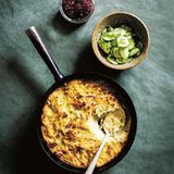 Kugelis aus Litauen      Zutaten:  140 g geräucherter Speck, gewürfelt 75 ml Milch, 2 Eier, 800 g mehligkochende Kartoffeln (z. B. Coliban, Désirée oder Russet), geschält, 150 g Zwiebeln, Salz, gemahlener weißer Pfeffer, 25 g Butter      Zum Servieren:  Apfelkonfitüre (oder Preiselbeerkonfitüre), saure Sahne, Gurkensalat      Zubereitung:  In einer Bratpfanne den Speck bei mittlerer Hitze braten, bis er gerade gebräunt ist. Milch angießen (dabei das ausgebratene Fett des Specks in der Pfanne lassen) und die Pfanne vom Herd nehmen.  Den Backofen auf 180 °C vorheizen.  Die Eier in einer großen Schüssel verquirlen und beiseitestellen. Kartoffeln und Zwiebeln auf einer feinen Handreibe reiben (das ist mit der Hand ziemlich viel Arbeit, wenn Sie also eine Maschine dafür haben, nutzen Sie sie). Geriebene Kartoffeln und Zwiebeln zu den verquirlten Eiern geben und alles gut verrühren. Dann die Speck-Milch-Mischung darübergießen und wieder alles gut vermischen. Mit 1 TL Salz und 1 kräftigen Prise Pfeffer würzen.  Die Butter in einer gusseisernen Pfanne schmelzen oder Boden und Seiten einer Auflaufform gleichmäßig mit der Butter bestreichen. Die Kartoffelmischung in die Pfanne oder Form gießen und im Backofen etwa 1 Stunde 30 Minuten backen, bis sie goldbraun ist. Mit Apfeloder Preiselbeerkonfitüre, saurer Sahne und Gurkensalat servieren.