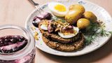 Baltischer Hering      Zutaten:  300 g Heringfillets mit Haut, 30 g Butter, 1 Zwiebel, gewürfelt, 2 EL Hanfsamen 700 g Babykartoffeln      Marinade:  4 Gewürznelken, 2 kleine Zimtstangen, 4 Lorbeerblätter, 1 EL schwarze Pfefferkörner, 80 ml Weißweinessig, 70 g Zucker, 200 g Heidelbeeren (gefroren oder frisch)      Zum Servieren:  8 Scheiben Roggenbrot, 2 hart gekochte Eier, halbiert, 30 g frischer Meerettich, geschält, Dillstängel          Zubereitung:  Heringsfilets abspülen und in 5 cm große Stücke schneiden. In ein großes sauberes Glas (oder zwei kleinere) füllen, dabei etwas Platz für die Marinade lassen.  Für die Marinade alle Zutaten außer den Heidelbeeren mit 150 ml Wasser in einem Topf zum Kochen bringen, dann vom Herd nehmen. Frische Heidelbeeren vorsichtig waschen. Dann die Heidelbeeren zum Wasser hinzufügen und die Marinade vollständig auskühlen lassen. Wenn sie kalt geworden ist, über den Hering gießen, sodass er davon ganz bedeckt ist. Verschlossen im Kühlschrank 2–3 Tage marinieren lassen.  In einer Bratpfanne die Butter schmelzen und darin die Zwiebel bei mittlerer Hitze anschwitzen. Die Hanfsamen hinzufügen und weitere 2–3 Minuten garen, bis die Samen leicht gebräunt sind. Dann die Pfanne vom Herd nehmen und die Mischung beiseitestellen. In einem Topf Wasser zum Kochen bringen. Die Kartoffeln hinzufügen und in etwa 10 Minuten weich garen. In ein Sieb abgießen.  Zum Servieren die marinierten Heringsstücke gleichmäßig auf die Teller aufteilen und die Hanfmischung daraufgeben. Dazu Kartoffeln, Brotscheiben und hart gekochte Eier servieren. Den frischen Meerrettich darüber reiben und das Gericht mit Dillstängeln garnieren.