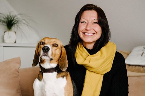 Beagle Toffee und seine dunkelhaarige Besitzerin. Sie trägt einen gelben Schal