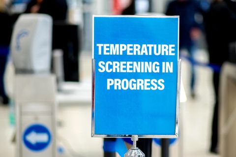 Ein Schild mit der Aufschrift "Temperature Screening in Progress" weist auf eine Einrichtung zur Messung der Körpertemperatur hin.