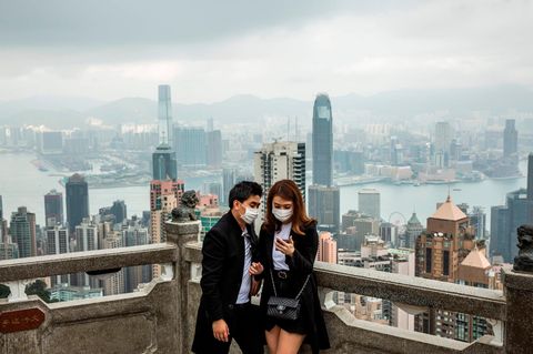 Ein Pärchen mit Mundschutz steht vor der Skyline Hongkongs