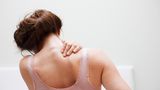 Frau reibt sich den Rücken