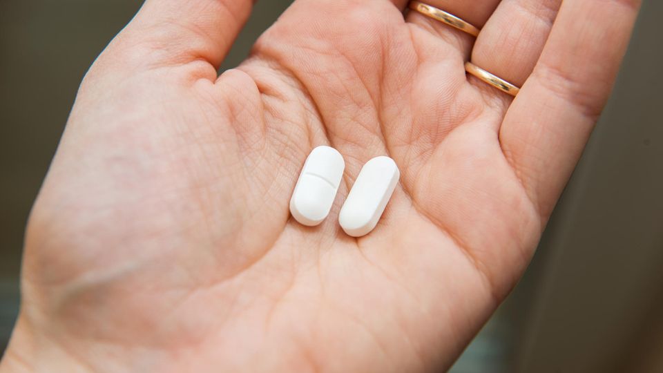 Ibuprofen und Coronavirus: Eine Frau hält zwei Tabletten in der Hand