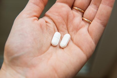 Ibuprofen und Coronavirus: Eine Frau hält zwei Tabletten in der Hand