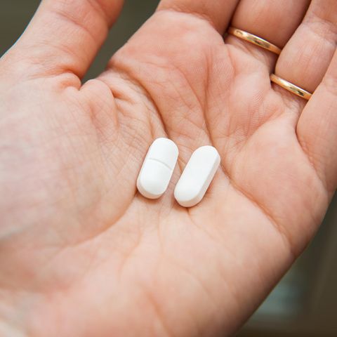 Ibuprofen und Coronavirus: Eine Frau hält zwei Tabletten in der Hand