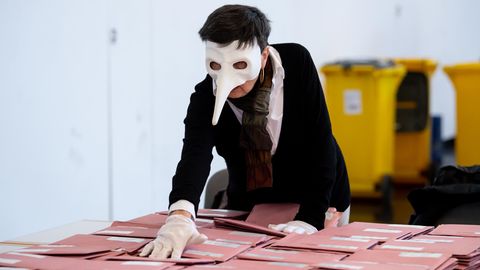 Eine Wahlhelferin mit einer Pestmaske bereitet in München die Auszählung der Briefwahl vor