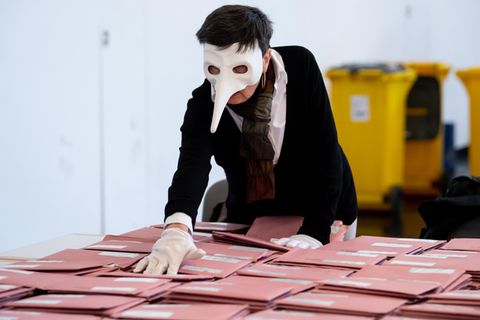 Eine Wahlhelferin mit einer Pestmaske bereitet in München die Auszählung der Briefwahl vor