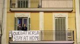 Die Katalanen nehmen es gelassen. Dieses Paar auf einem Balkon in Barcelona applaudiert einem Flashmob und hält sich an das Motto: "Bleib zuhause".