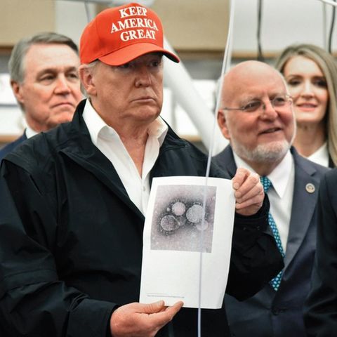 Donald Trump hält ein Bild des Virus in die Kamera