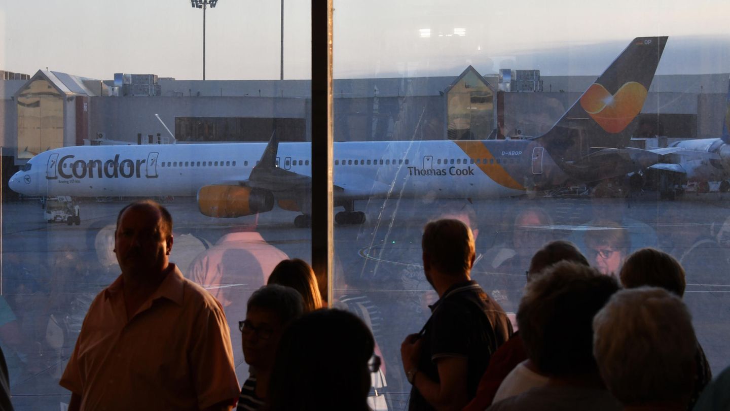 Passagiere schauen auf das Rollfeld, wo ein Flugzeug steht