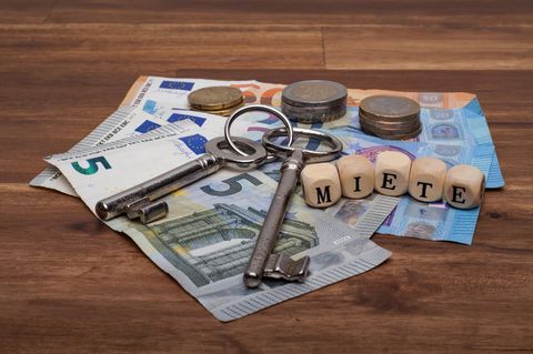 Geld auf dem Tisch mit zwei Schlüsseln und Würfel mit der Aufschrift "Miete"