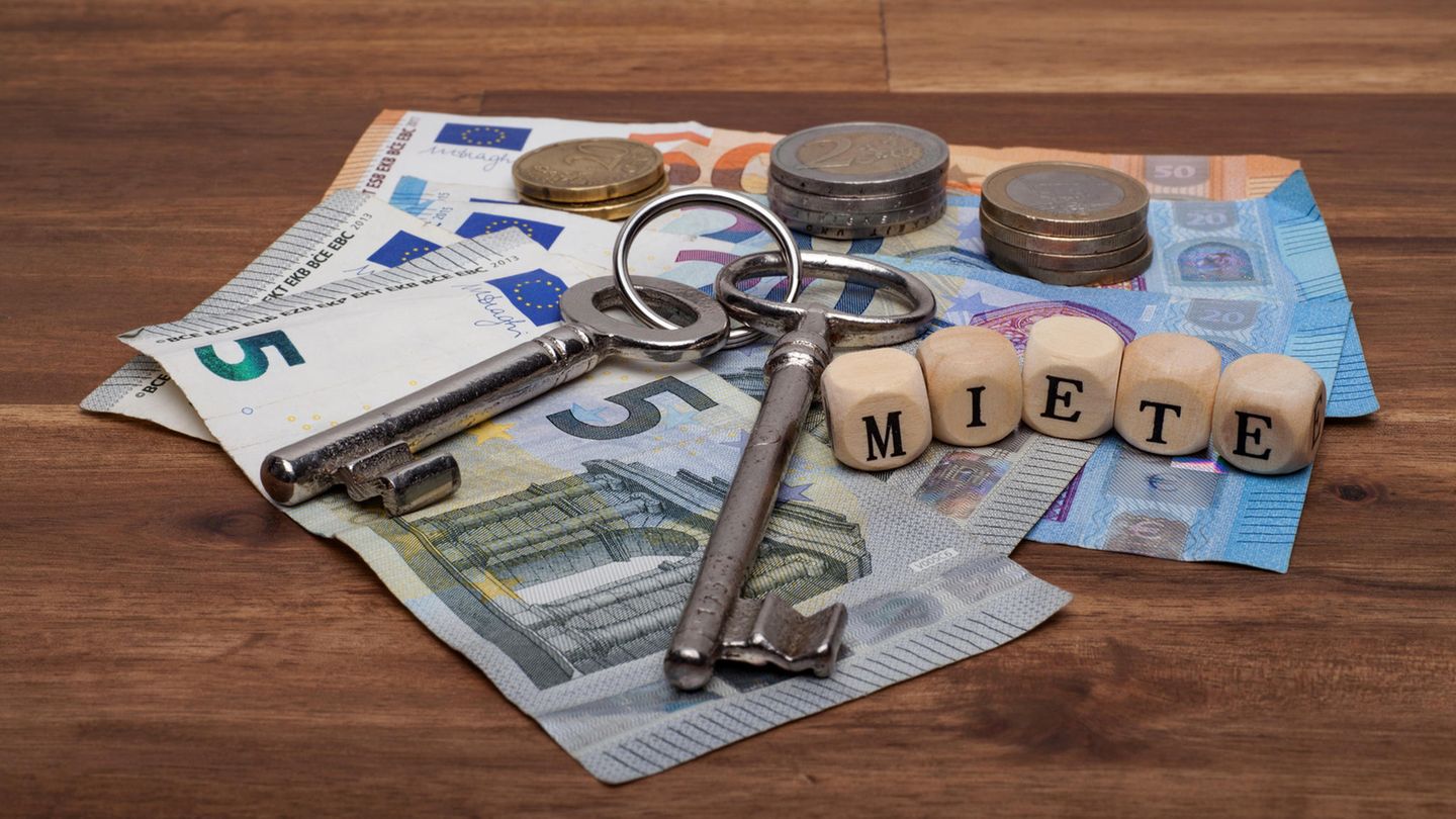 Geld auf dem Tisch mit zwei Schlüsseln und Würfel mit der Aufschrift "Miete"