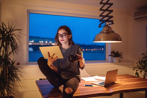 Eine junge Frau sitzt im Home Office und schaut auf ihr iPad