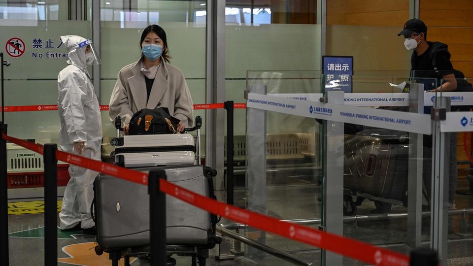 Eine Frau kommt am Shanghai Pudong International Airport an und wird von Sicherheitskräften auf Anzeichen für Corona gecheckt Eine Frau kommt am Shanghai Pudong International Airport an und wird von Sicherheitskräften auf Anzeichen für Corona gecheckt