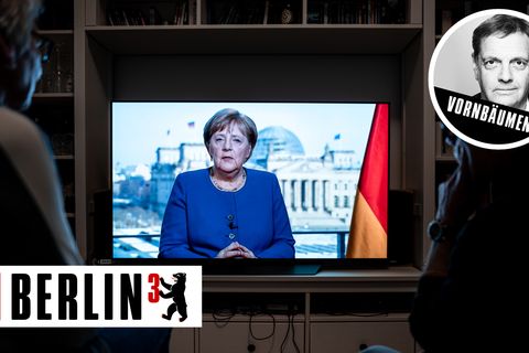 Zwei Menschen sehen die Rede von Bundeskanzlerin Angela Merkel (CDU)
