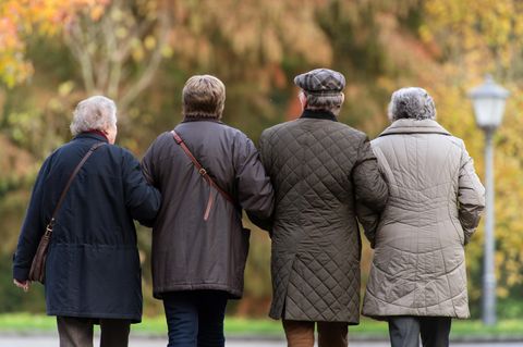 Vier ältere Menschen laufen Arm in Arm