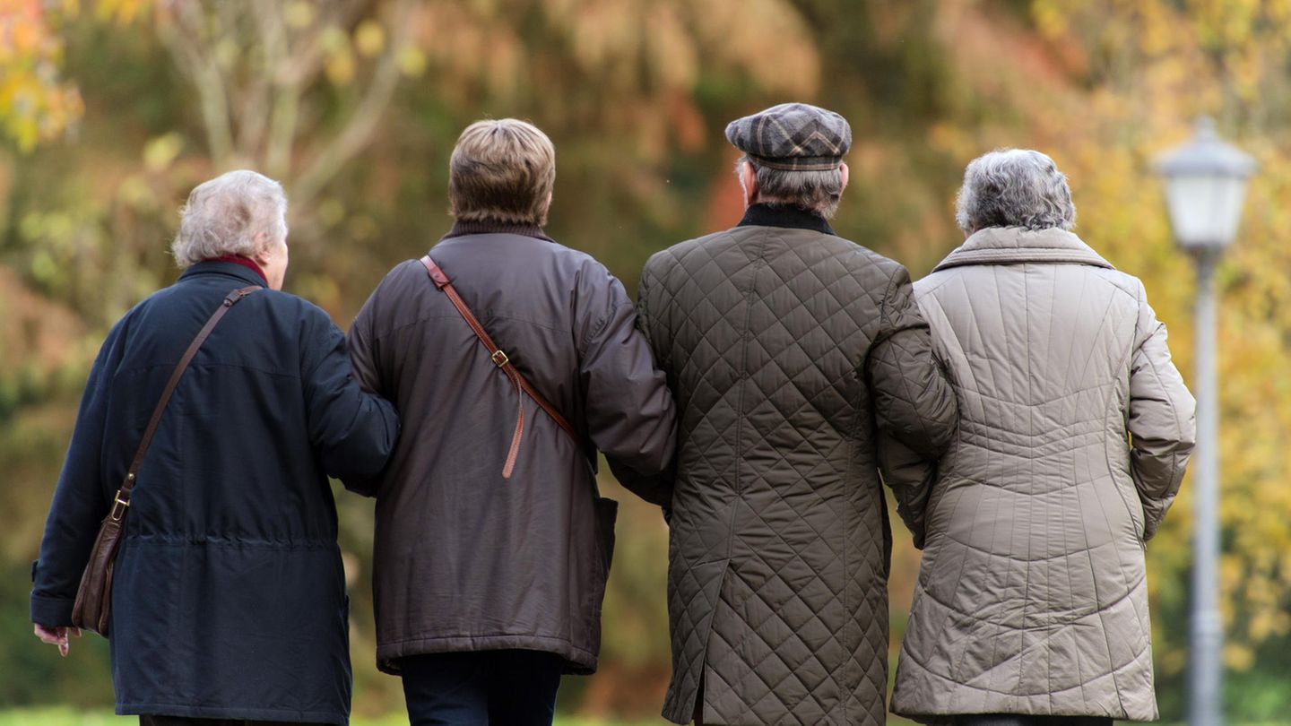 Vier ältere Menschen laufen Arm in Arm