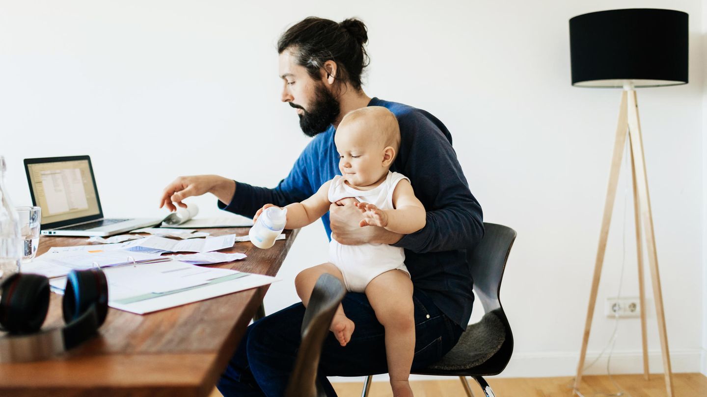 Vater sitzt mit seinem Baby am Computer