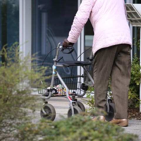 Bayern, Würzburg: Ein ältere Frau mit Rollator geht vor dem Eingang eines Senioren-Wohnstiftes